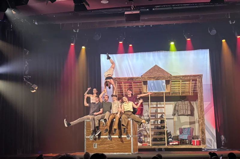 Die Künstler*innen sitzen vergnügt in ihrem Dachboden, während eine kopfüber auf den Köpfen turnt. | © GOP Variete Theater