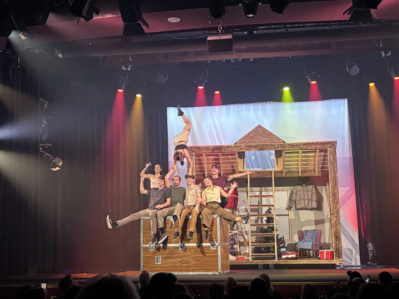 Die Künstler*innen sitzen vergnügt in ihrem Dachboden, während eine kopfüber auf den Köpfen turnt. | © GOP Variete Theater