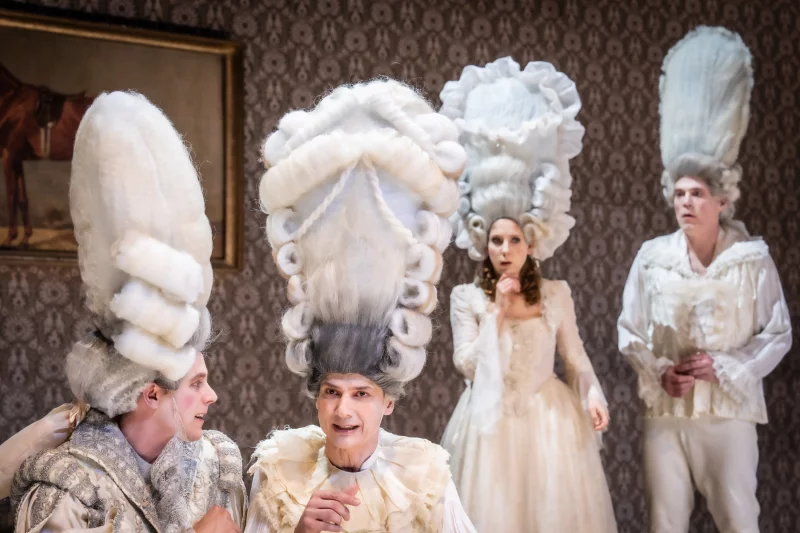 Vier Schauspielende tragen hohe barocke Perrücken. Zwei Personen unterhalten sich angeregt. | © Matthias Jung