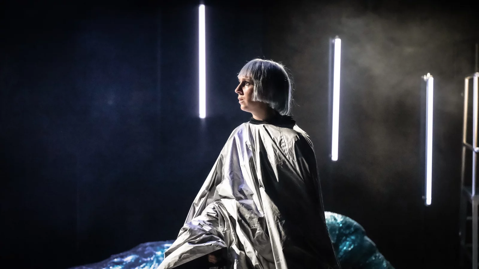 Eine Dame mit weißer Perrücke und silbernem Outfit sitzt enttäuscht auf der Bühne im dunklen Licht. | © Sandra Then